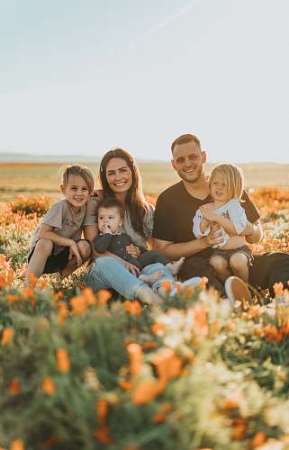 family 3 women and 2 men sitting on green grass field during daytime person