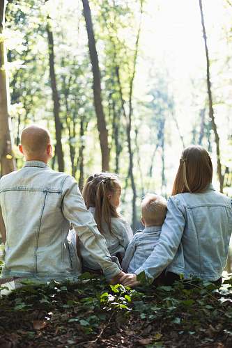 family man and woman holding hands together with boy and girl looking at green trees during day people