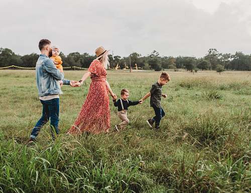 family woman holding man and toddler hands during daytime field