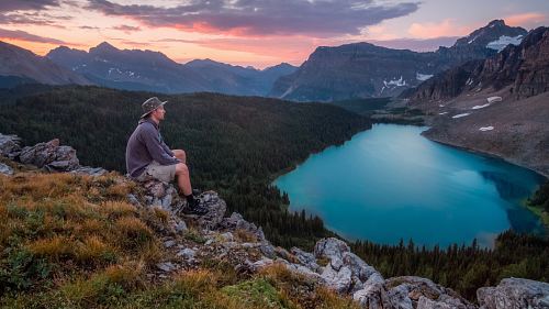 man looking on mountain sitting on rock