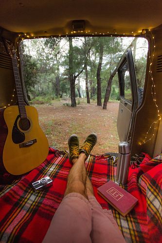 person sitting inside vehicle near brown acoustic guitar