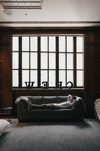 photo of person laying on sofa near window