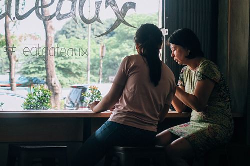 women sitting on black wooden stools