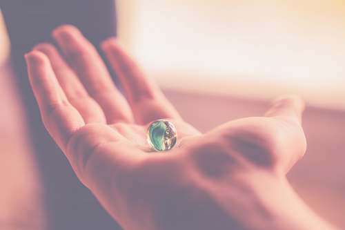hand persons hand holding blue and clear marble toy marble