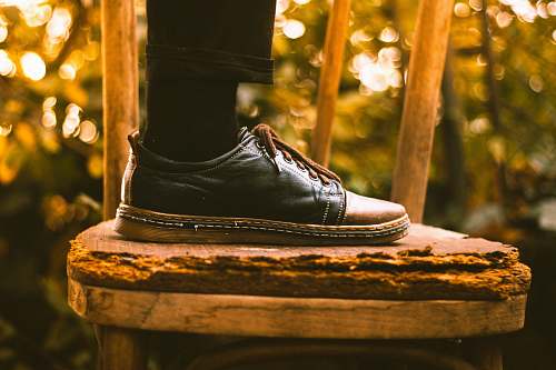 bokeh person wearing black dress shoe stepping on chair worship