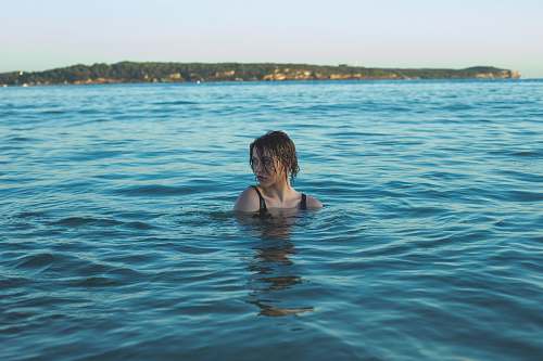 swimming photography of woman in black swimming wear soaked in sea people
