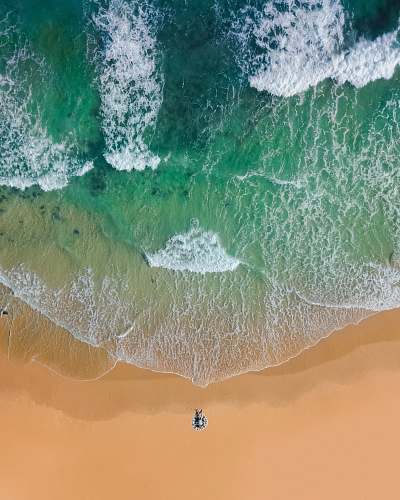 water top view photography of brown sand on beach with teal ocean water during daytime ocean