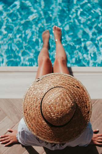 people woman sitting on poolside setting both of her feet on pool woman