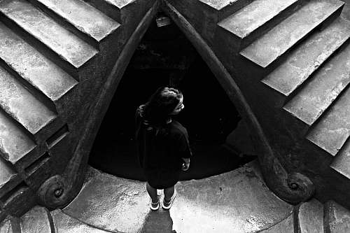human grayscale photo of woman standing near stairs person