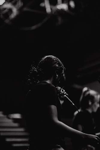 person grayscale photography of person holding microphone human