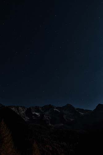 night gray and brown mountains under starry night photo outer space