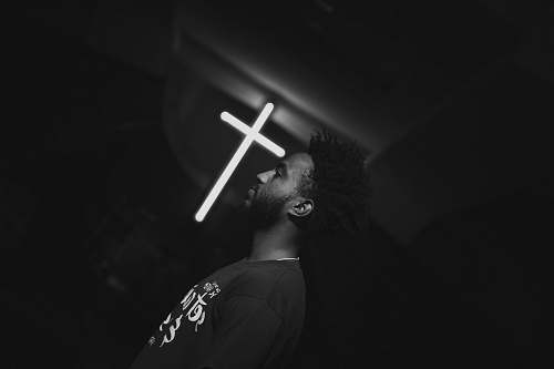 black-and-white man beside cross cross