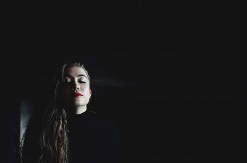 human woman wearing black crew-neck top inside black room person