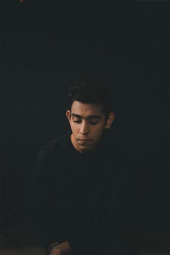 person man wearing black long-sleeved shirt sitting while looking down people