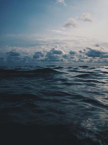 water sea under white clouds during daytime sea