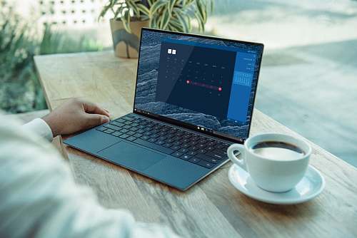 electronics person using black laptop computer on brown wooden table pc