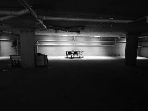 black-and-white table with chairs near wall in a dark room parking lot
