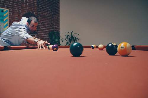 person man playing billiard near green leafed plants people