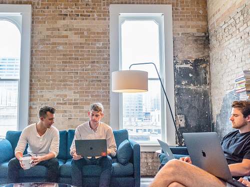 couch three men using MacBooks furniture