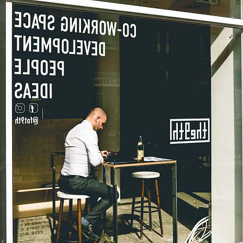 human man sitting on chair while using smartphone during daytime sitting