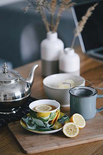 saucer gray teapot beside mug filled with tea and lemon on top of table tea
