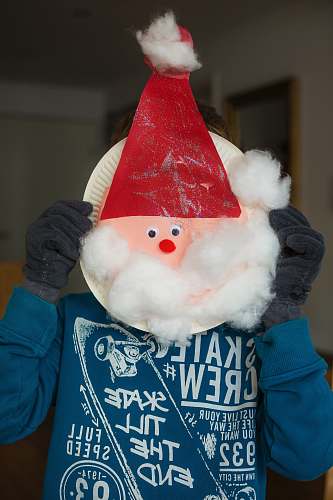 red person holding white paper plate with Santa head inside room father christmas